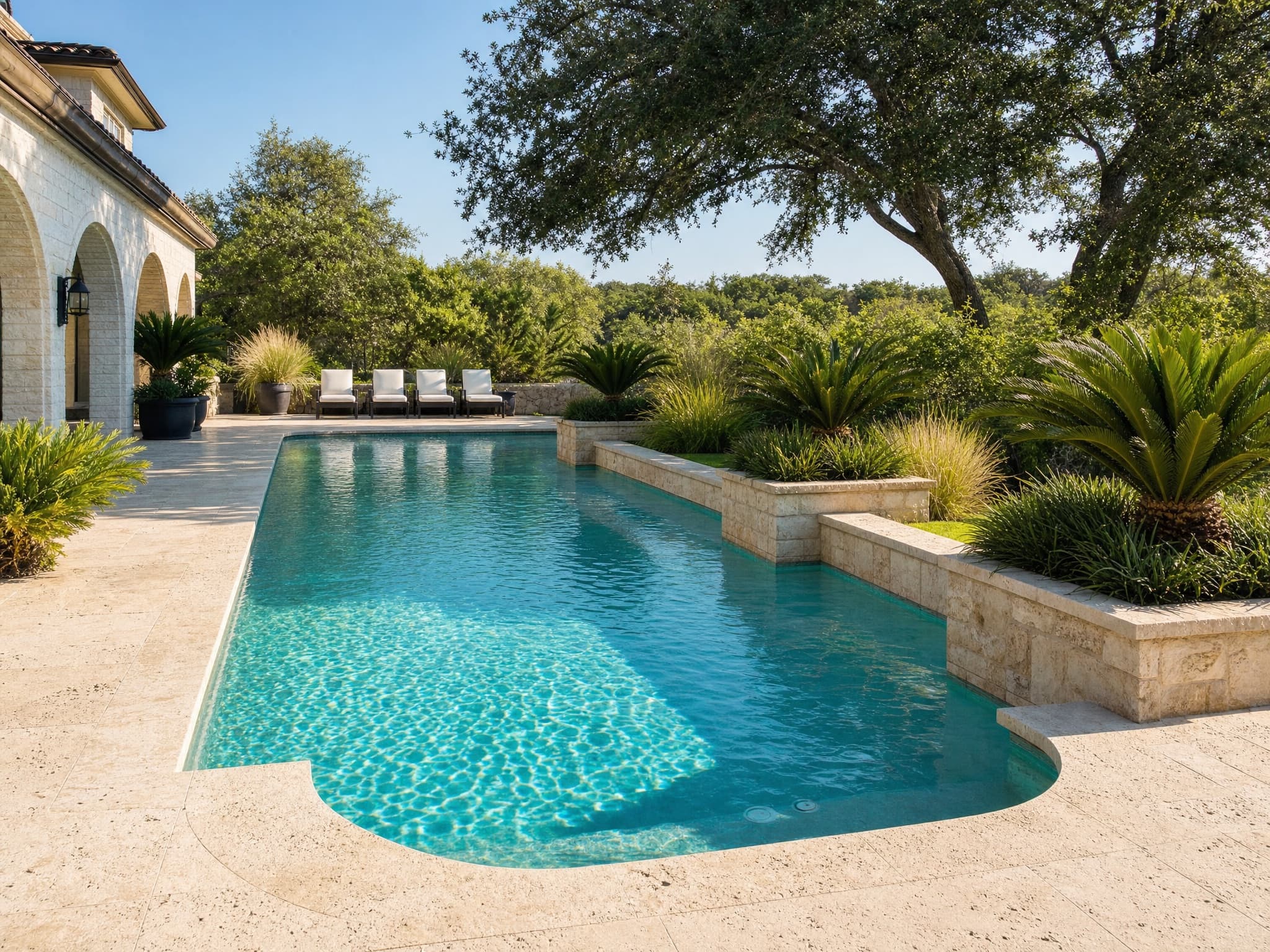 Travertine pool deck with limestone planter walls, sago palms, and loungers in Colleyville